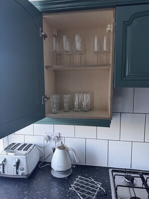 A kitchen with a built-in cabinet containing wine glasses and a coffee maker on the counter. - Spacious Newly Reno 3BR Home with Garden | Sleeps 7 | Near BHX Airport NEC & HS2 (Birmingham)