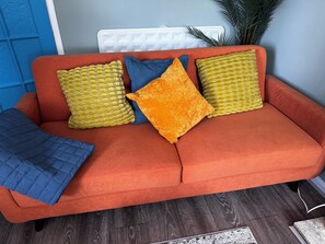 Ein rotes Sofa mit drei Kissen in verschiedenen Farben und Texturen.