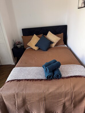 A neatly made bed with a brown bedspread, a dark headboard, and decorative pillows. - Spacious Newly Reno 3BR Home with Garden | Sleeps 7 | Near BHX Airport NEC & HS2 (Birmingham)