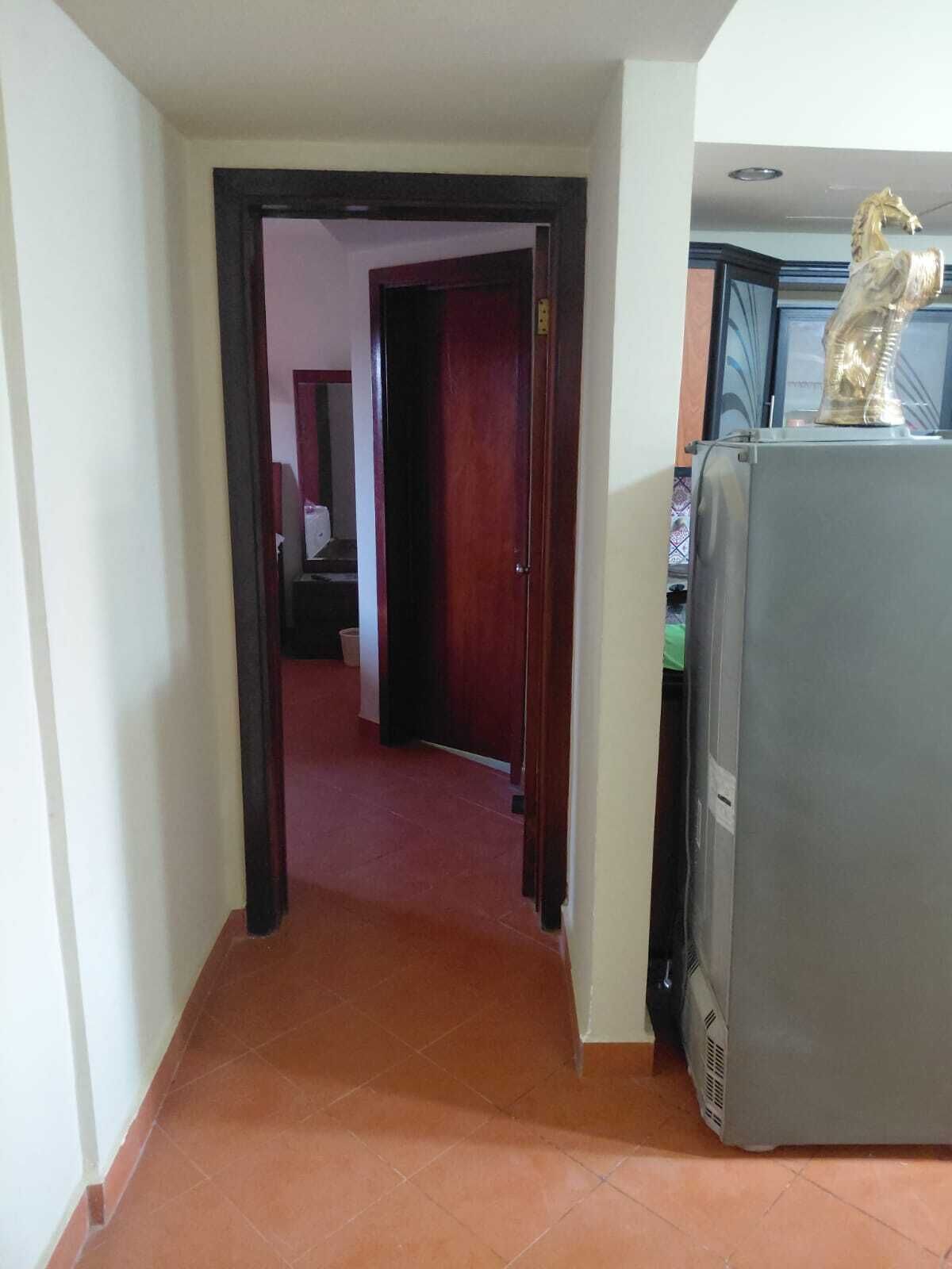 Ein Korridor mit einem Kühlschrank und einer Statue auf der rechten Seite.