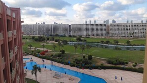 Ein Hotel mit Swimmingpool, Golfplatz und Blick auf hohe Gebäude.