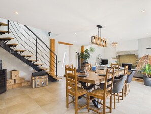 A spacious dining area with a wooden table and chairs, a staircase with wooden steps, and a hanging light fixture. - Quiet house with large garden - 7 guests (Plouguerneau)