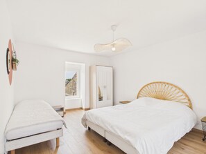 Une chambre avec deux lits, une porte donnant sur l’extérieur et un luminaire suspendu.