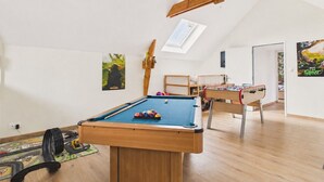 Ein Zimmer mit Billardtisch, Holzbalkendecke, Oberlicht und einem Charakterplakat.