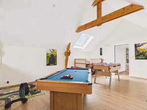 Ein Zimmer mit Billardtisch, Holzbalkendecke, Oberlicht und einem Charakterplakat.