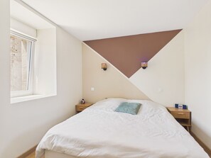 A bedroom with a bed, a window, a nightstand, and a wall-mounted lamp. - Quiet house with large garden - 7 guests (Plouguerneau)