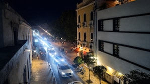 A nighttime street scene with buildings, vehicles, and pedestrians. - Room-balcony Street View Bedroom Zona Co (Santo Domingo)