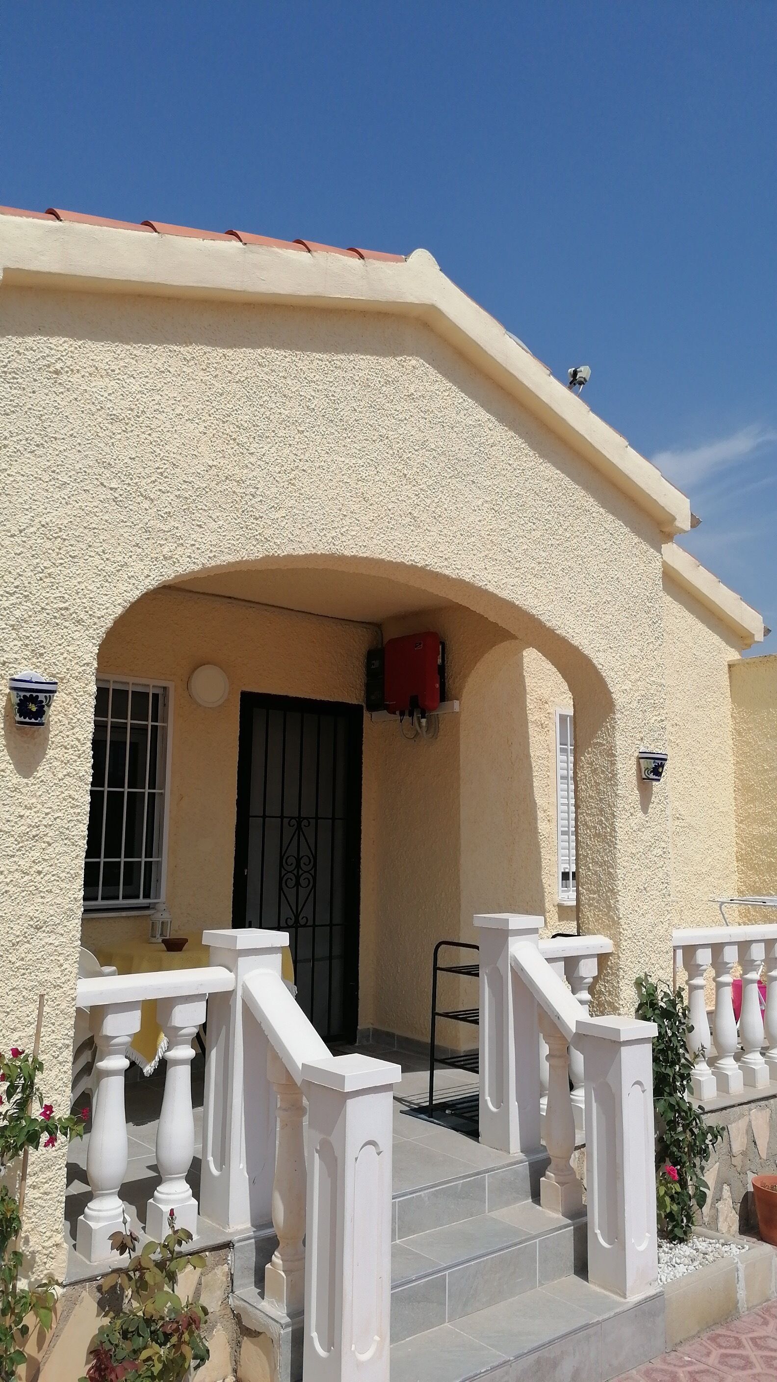 A building with a textured facade, a black door, and a white staircase leading to the entrance.