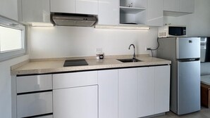 Eine moderne Küche mit weißen Schränken, einem Edelstahl-Kühlschrank, einer Mikrowelle und einem eingebauten Backofen.