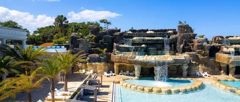 Un resort con una amplia piscina, una cascada y sillas de descanso.