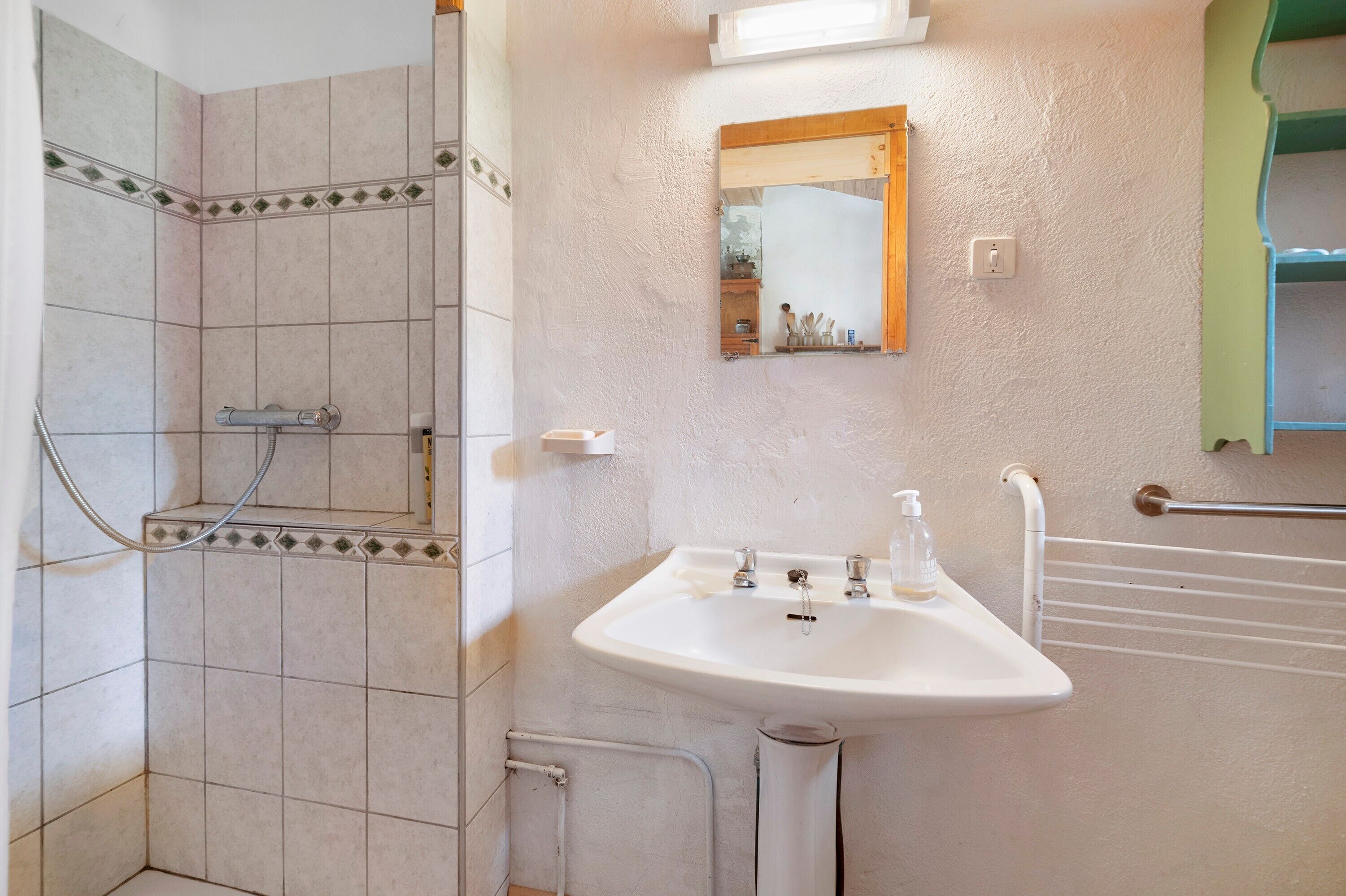 Un baño con ducha, lavamanos y espejo.