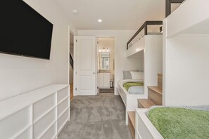 A narrow hallway with a TV mounted on the left wall, a staircase on the right, and a door leading to a bathroom. - Splash and Swing: Desert Color Lagoon + Beaches (St. George)