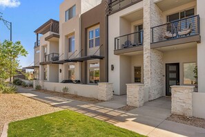 A multi-story residential building with balconies, stone accents, and a well-maintained lawn. - Splash and Swing: Desert Color Lagoon + Beaches (St. George)