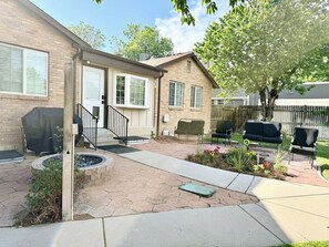 A residential backyard with a brick house, a covered grill, a fire pit, outdoor seating, and a wooden deck. - Executive Sloan’s Lake Charmer (Denver)