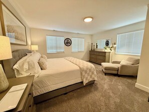 A bedroom with a bed, bedside tables, a dresser, a chair, and a clock on the wall. - Executive Sloan’s Lake Charmer (Denver)