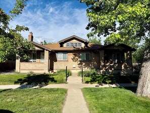 A two-story house with a brick facade, a front porch, and a pathway leading to the entrance. - Executive Sloan’s Lake Charmer (Denver)