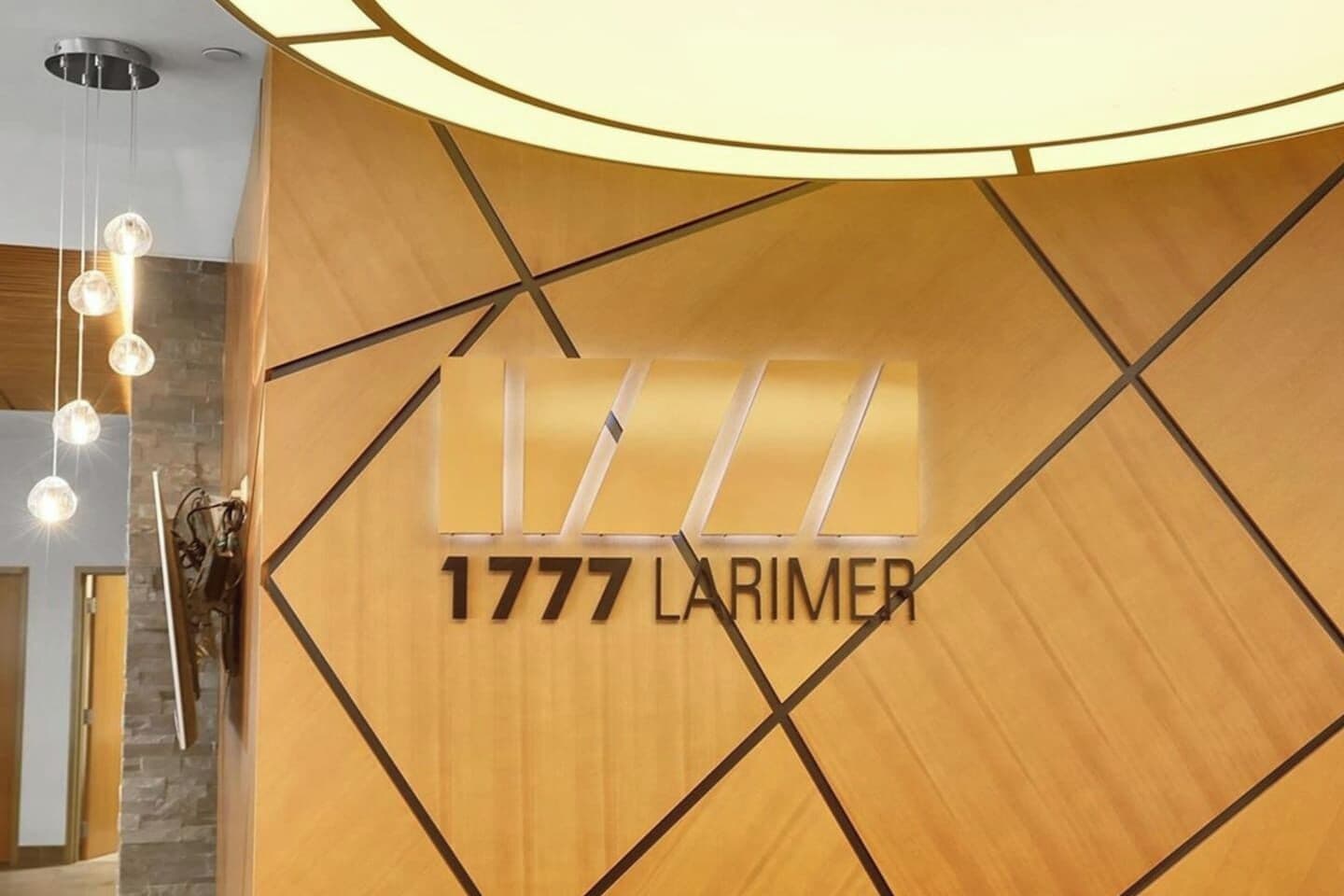 A hotel reception area with a wooden wall and a modern light fixture.