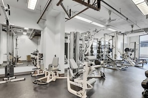 A gym with various exercise equipment, mirrors, and a ceiling with exposed pipes. - Fun Downtown Denver (LoDo) Condo + Free Parking (Denver)