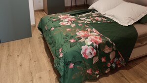 A bedroom with a sloped ceiling, a bed with floral bedding, a chair, and a window.