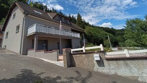 A two-story building with a balcony, a covered entrance, and a gravel driveway.