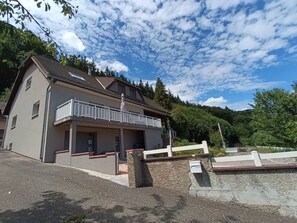 A two-story building with a balcony, a covered entrance, and a gravel driveway.