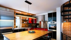 Een moderne keuken met roestvrijstalen apparatuur, een houten kookeiland en rode keukenkastjes.