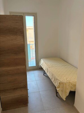 A room with a bed, a wooden wardrobe, and a door leading to an outdoor area. - Apartment in a Villa, 30 meters from the beach (Agnone)
