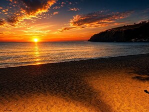 A beach with a sunset, calm sea, and a cliff in the background. - Apartment in a Villa, 30 meters from the beach (Agnone)