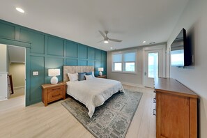 Ein Schlafzimmer mit Bett, Nachttischen, einem Schminktisch und einem Deckenventilator, sowie einem Fernseher.