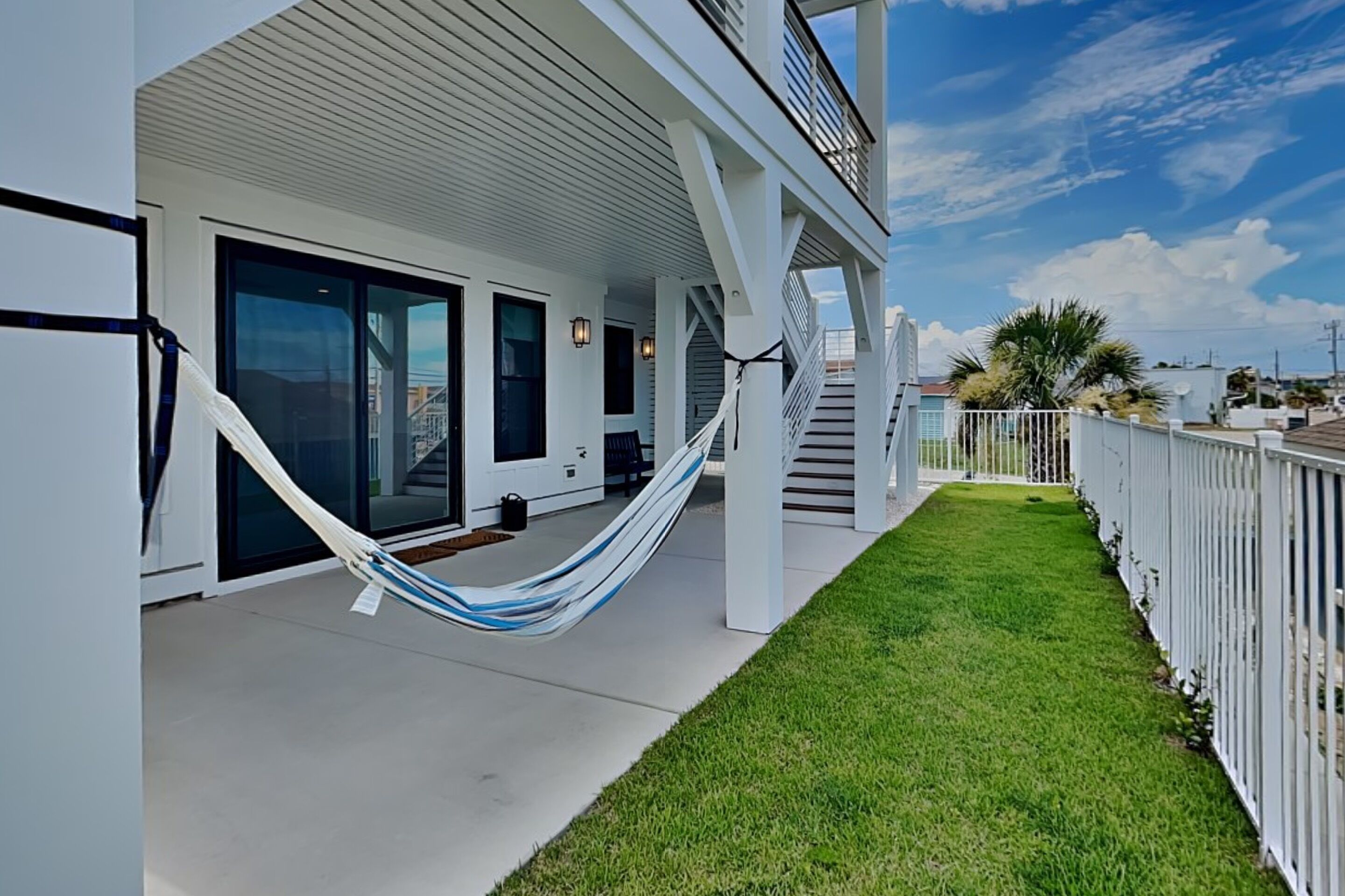 A modern building with a covered porch, a hammock, and a well-maintained lawn.