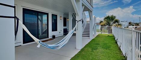 A modern building with a covered porch, a hammock, and a well-maintained lawn.