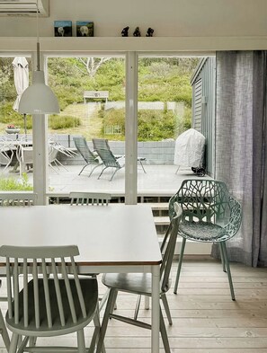 Une terrasse avec une table et des chaises, un barbecue couvert et une vue sur la verdure.