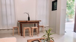 A room with a bed, a wooden table with four stools, a potted plant, and a window with curtains. - 1BR Apartment Beach Getaway Perfect for Couples (San Fernando)