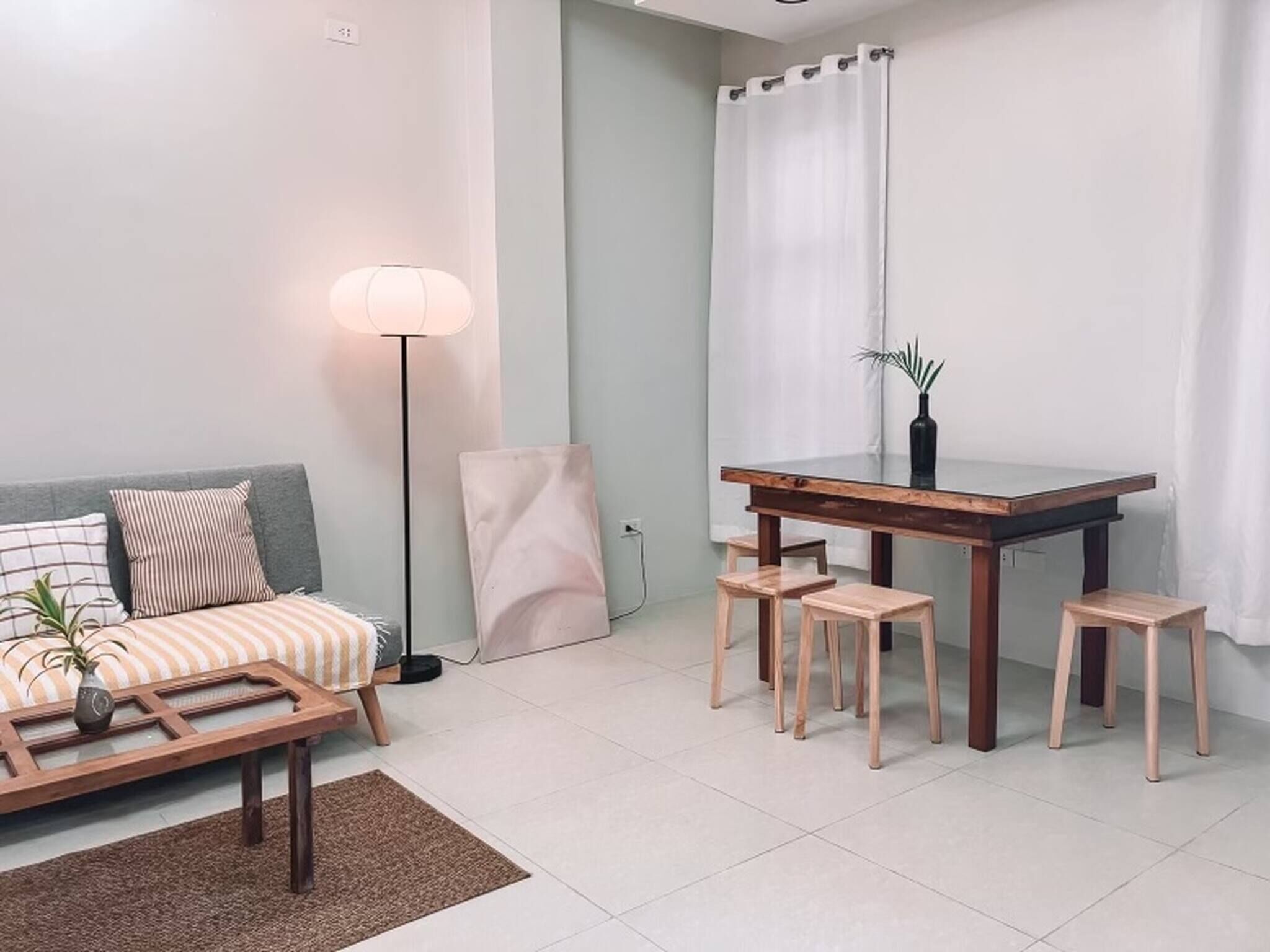 Ein Wohnzimmer mit Sofa, Couchtisch, Stehlampe und einem Esstisch mit Hockern.