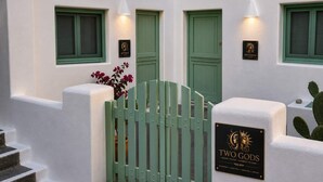 Ein Gebäude mit grünen Türen, einem Tor und einer Plakette mit der Aufschrift 'Two Gods' und 'Zimmer zum Übernachten, Erinnerungen für immer'.