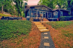 A modern house with a covered patio, outdoor seating, and a stone pathway leading to the entrance. - Relaxing Badin Lake Waterfront l Private Pier,Hot Tub,Pool Table-Dock Your Boat! (New London)
