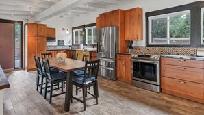Una cocina moderna con armarios de madera, electrodomésticos de acero inoxidable y un comedor amplio.