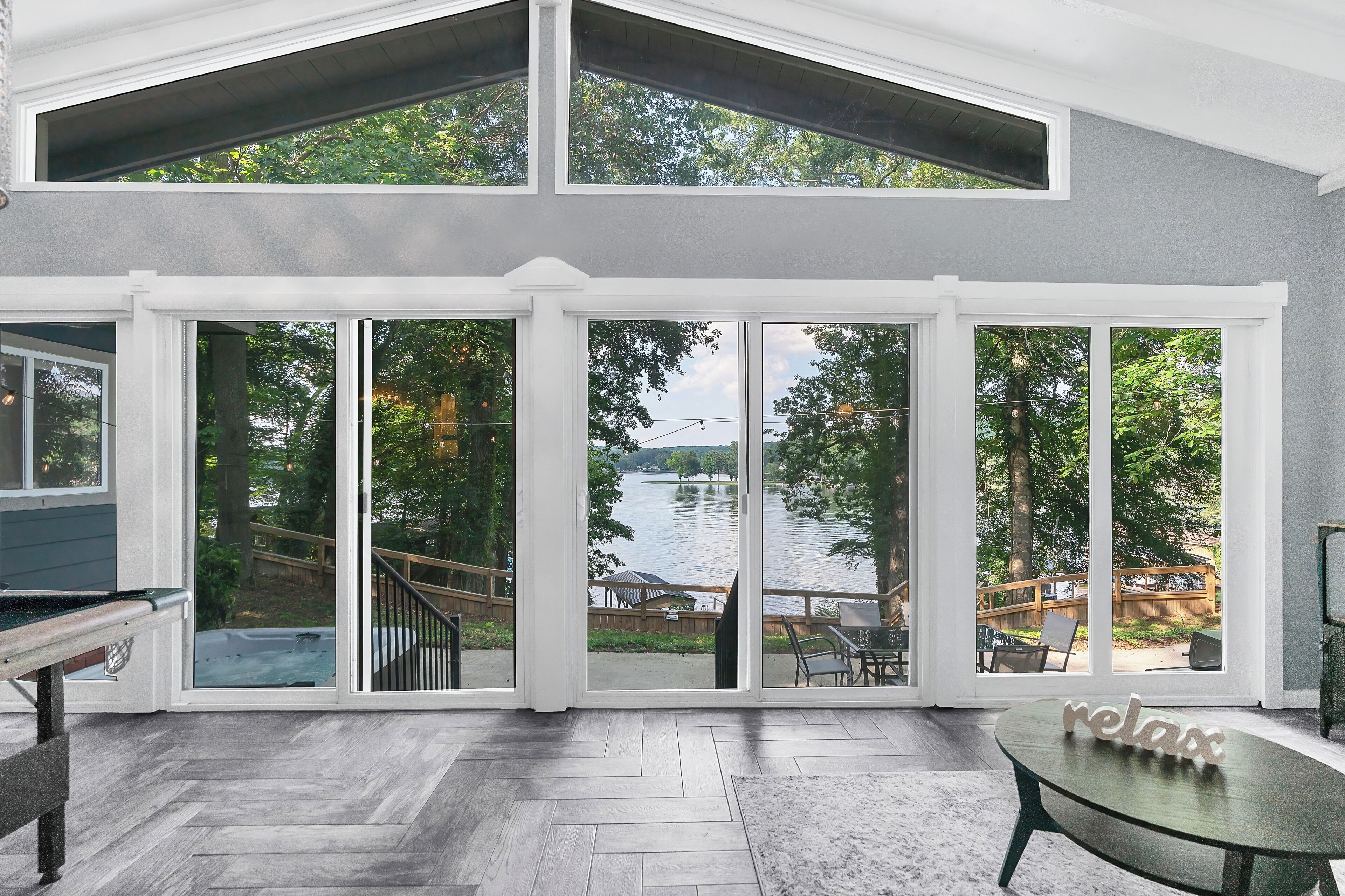 A spacious room with a large sliding glass door leading to a deck with a view of a lake.