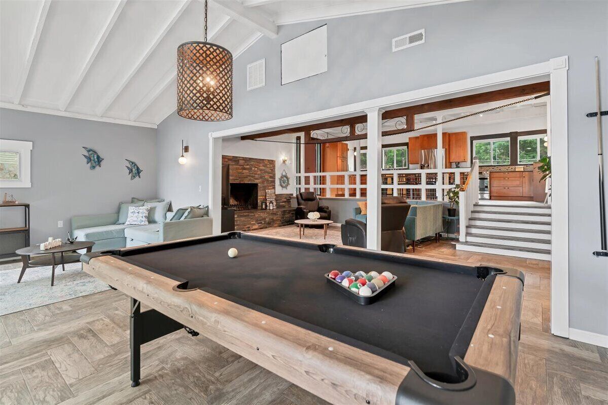 A pool table in a room with a fireplace, a sofa, and a dining area.