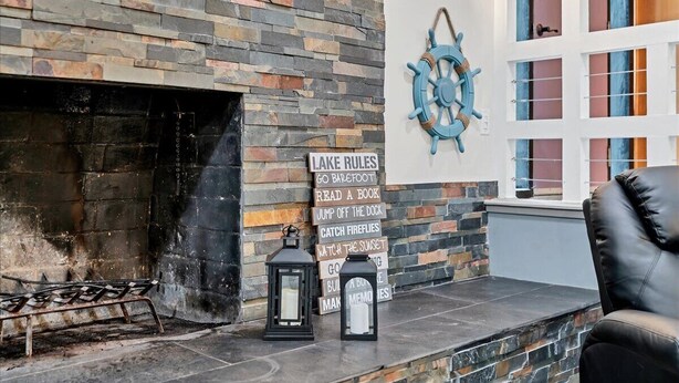 Una chimenea de piedra con un cartel que enumera actividades, un farolillo y una decoración de rueda de barco.