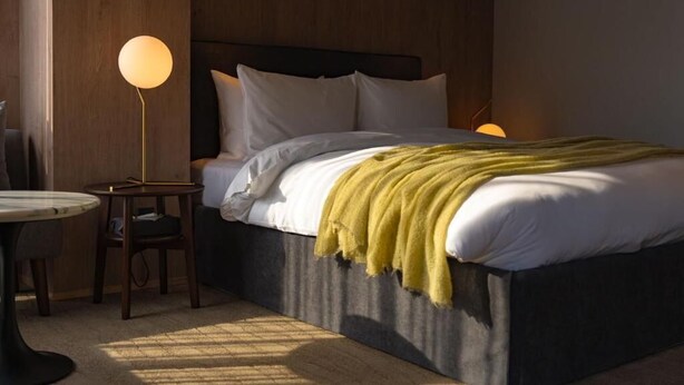A bedroom with a bed, bedside table, lamp, and a view of the outside. - The 1898 Niseko (Kutchan)