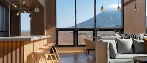 A modern interior with a bar area, seating, and large windows offering a mountain view.