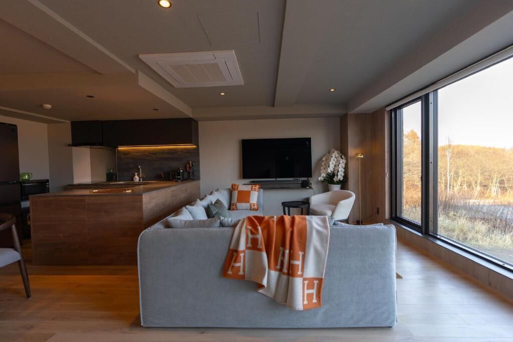 A modern living room with a sofa, a television, and a large window.
