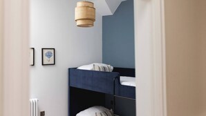 Quarto com beliche, luminária pendente, quadro na parede e radiador.