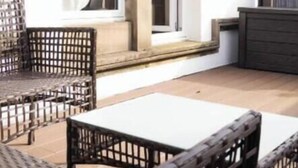 Um pátio com móveis de vime e uma mesa branca.