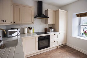 A modern kitchen with a built-in oven, a microwave, and a toaster. - Luxury 3-Bed Apartment in the Heart of Ambleside (Ambleside)