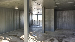 A corridor with concrete walls and a metal gate at the end. - Shore to Please: Oceanfront, Pool, Classic Beach Charm (Murrells Inlet)