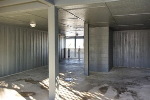 Ein Korridor mit Betonwänden und einem Metallgitter am Ende.