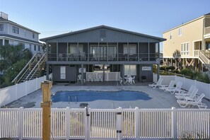 Ein zweistöckiges Gebäude mit Pool, Außenbereich und umzäunter Fläche.