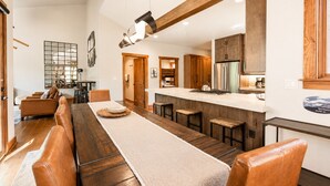 Un espacio habitable amplio con un largo banco de madera, una cocina con armarios de madera y una zona de bar.